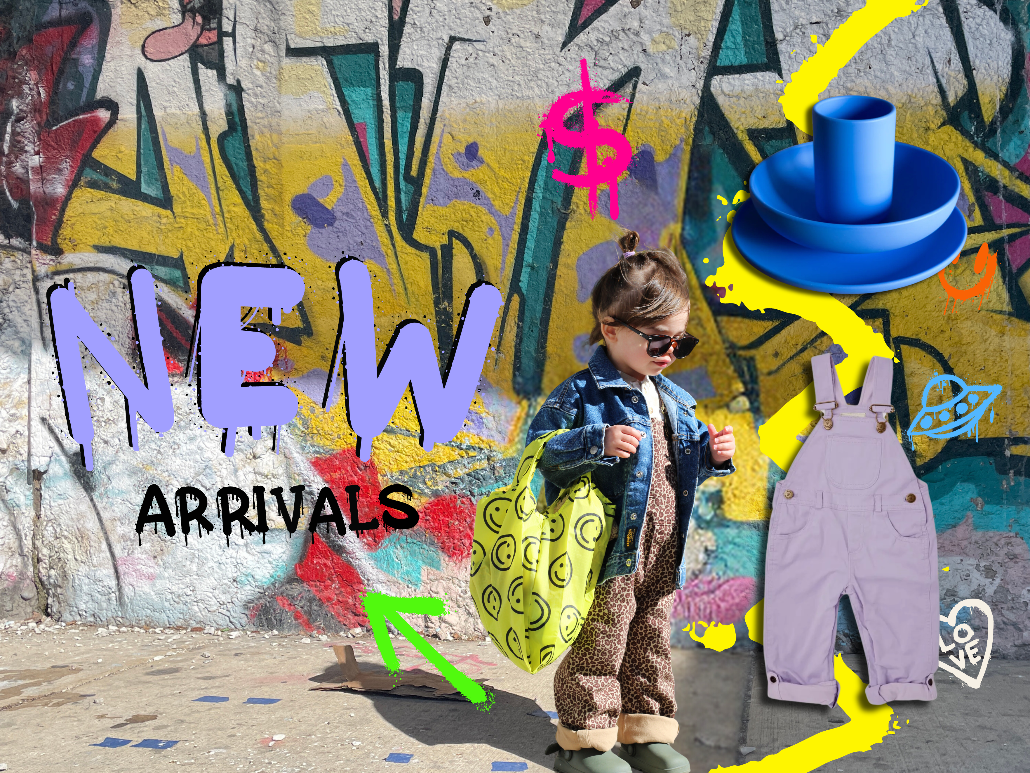 first slideshow image to promote new kids clothing arrivals for spring. A young child about 2 years old stands in front of a colorful graffiti mural holding a reusable bag with smiley faces and wearing a blue denim jacket and leopard overalls. On the right of the screen shows lavender overalls and a cobalt blue silicon dish set and cup. 