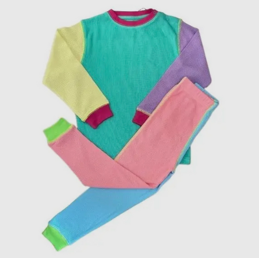 flat lay photo of waffle pajamas for kids. bright green cuffs, pink and blue pant legs, turquoise shirt with one yellow arm and one lilac arm. 